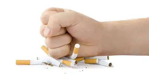 Mano sobre cigarrillos rotos Imagen de una mano sobre cigarrillos rotos