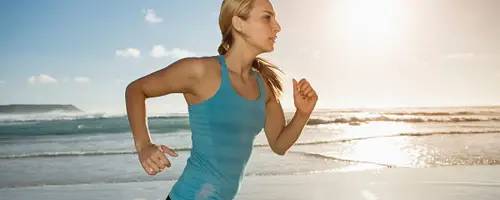 Mujer haciendo deporte. Clínica Universidad de Navarra Imagen de una mujer deportista, corriendo por la playa.