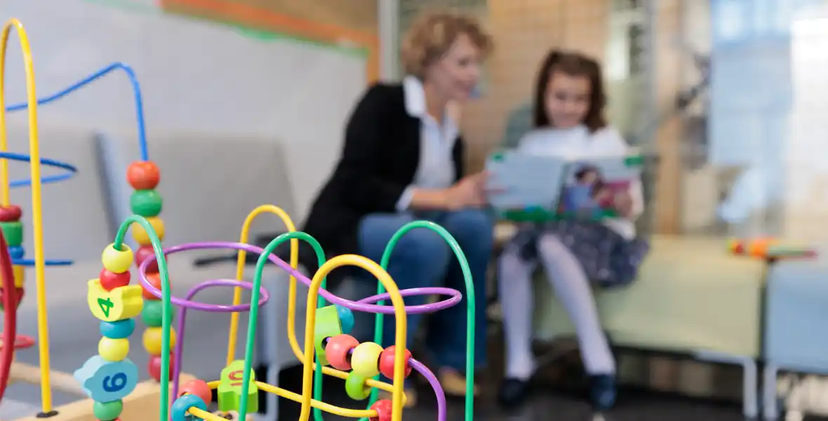 Imagen de una madre y su hija leyendo un libro en la sala de espera de Pediatría en la Clínica Universidad de Navarra.